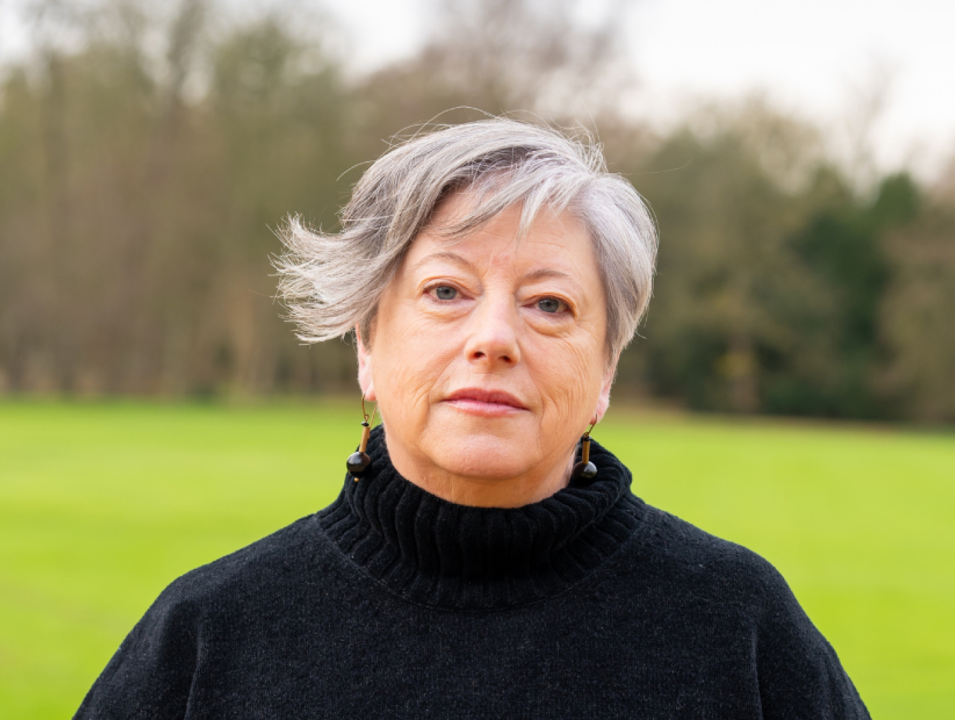 Vona Groarke, poses for a photograph. They are wearing a black polo neck jumper and have short hair with a sweeping fringe.