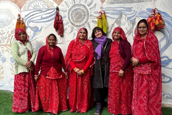 women standing in front of an Indian Mural looking at the camera and smiling