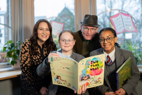 two girls looking at books with a man and woman looking at the camera