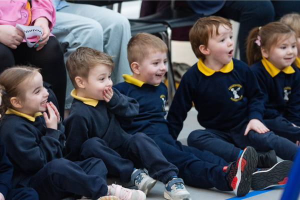 Children sitting in a row laughing and smiling