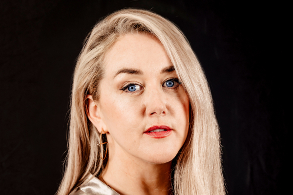 Headshot of blonde woman against a black background