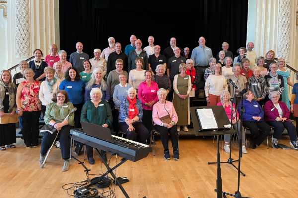 A group of adults of various ages lined up in rows in front of a stage