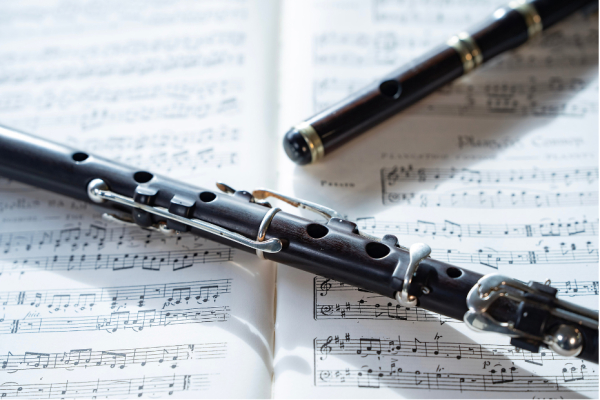 white sheet of music with a black flute lying on top of it