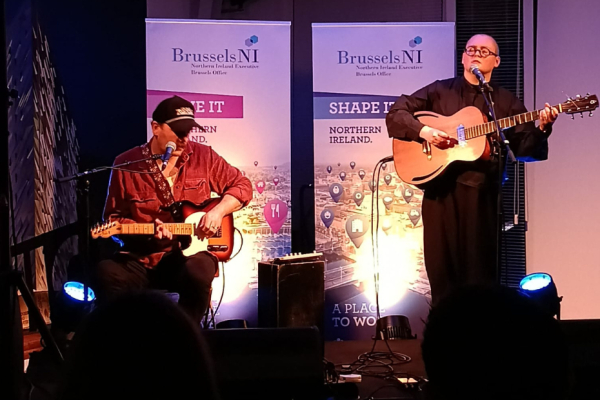 A man playing a guitar and a woman playing guitar and singing on a stage