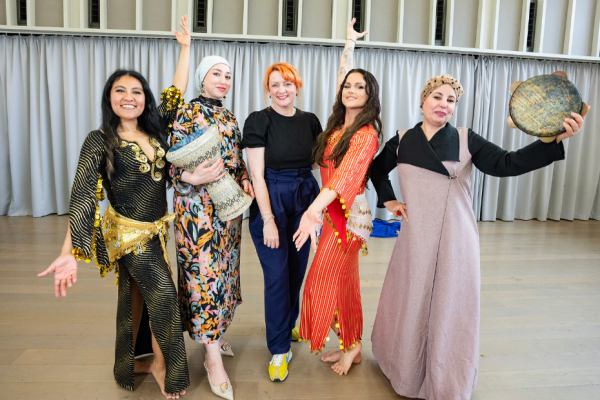 Five people standing in a dance pose smiling towards the camera.