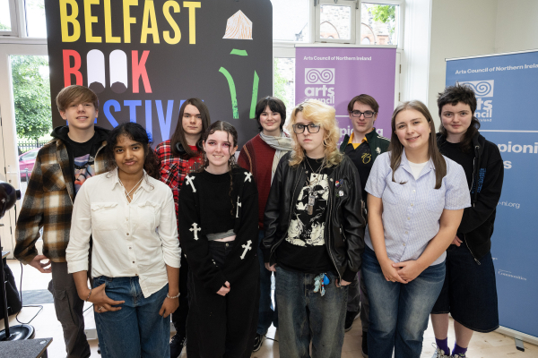 Young people standing together indoors smiling towards to the camera.