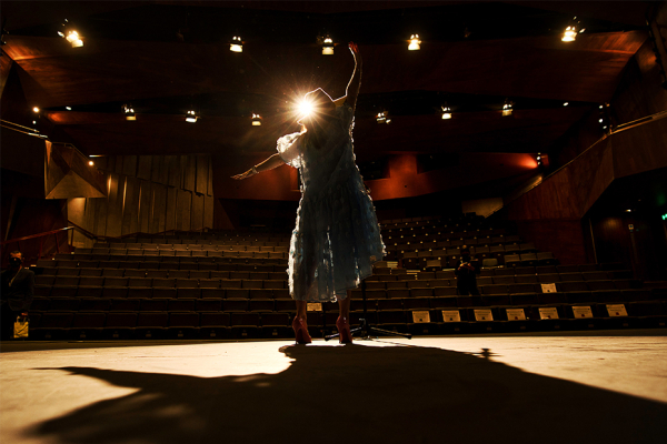Dancer wearing blue dress performing on stage.