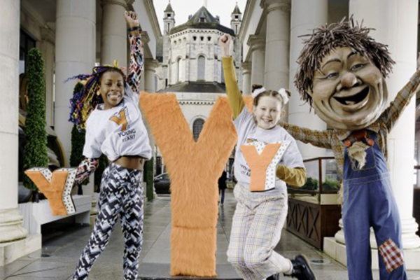 Two young girls jumping in St Anne’s Square Belfast wearing Young at Art branded t-shirts