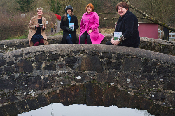Creative Writing Tutor Shelley Tracey, Maire Gaffney from the Waterways Storymaking Festival, Rhonda Glasgow (Photography Category Winner at the 2021 festival) and Sonya Whitefield, Arts Council of Northern Ireland sitting on a small bridge.