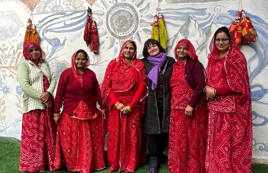 women standing in front of an Indian Mural looking at the camera and smiling