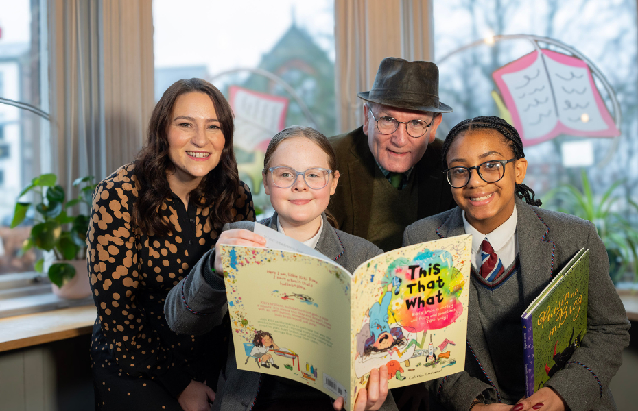 two girls looking at books with a man and woman looking at the camera