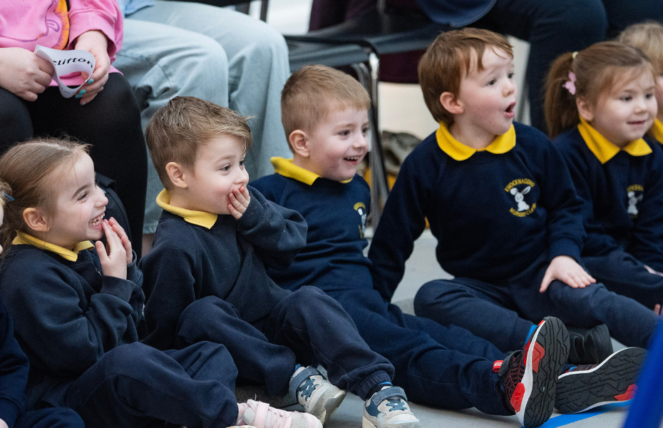 Children sitting in a row laughing and smiling