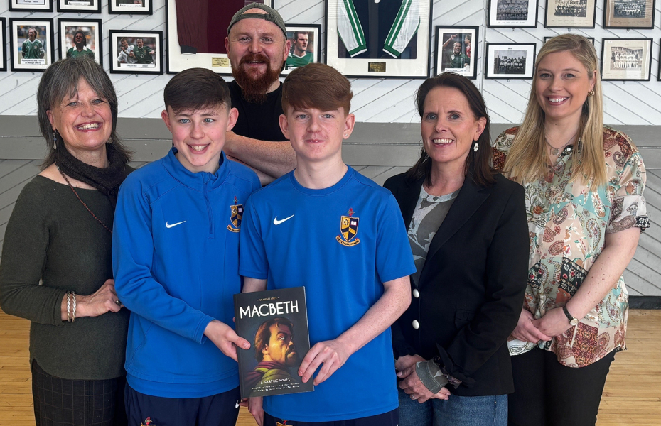 Two school pupils holding a macbeth book with four adults standing in a line