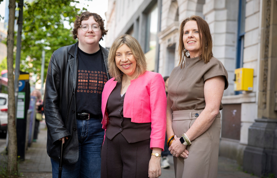 three people standing in the street in a row smiling at the camera