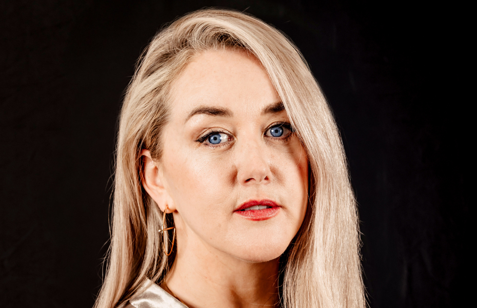 Headshot of blonde woman against a black background