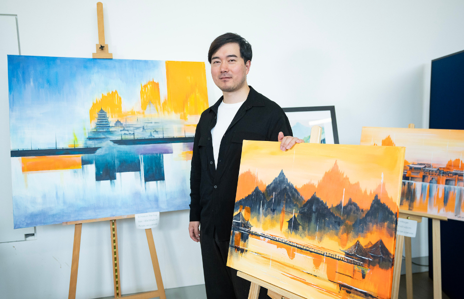 A man standing between two paintings on easels