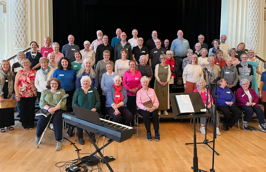 A group of adults of various ages lined up in rows in front of a stage