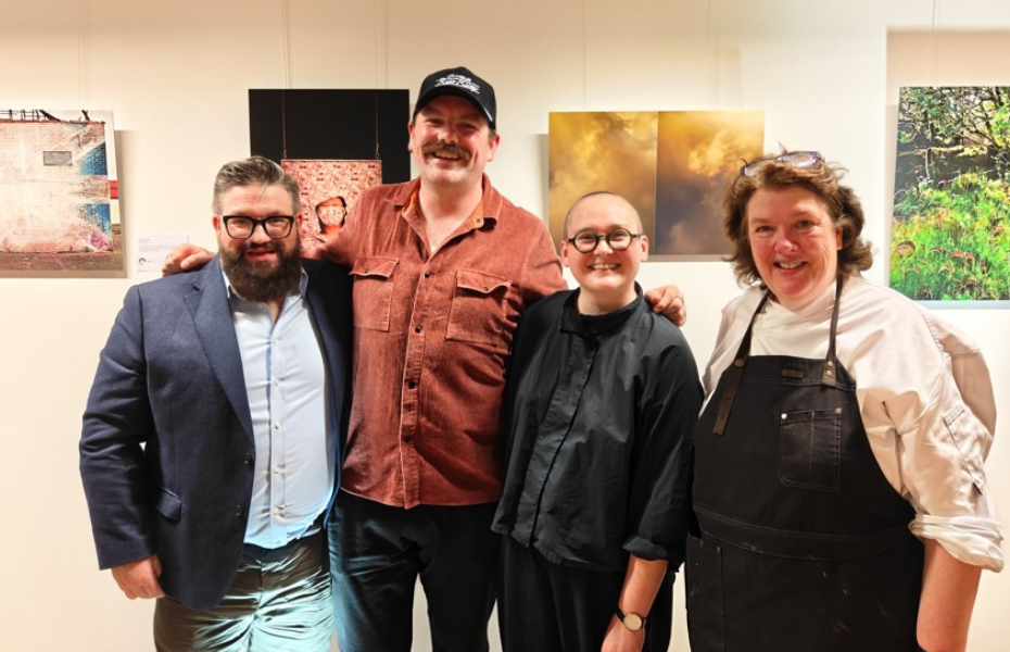 4 adults standing in a row smiling at the camera