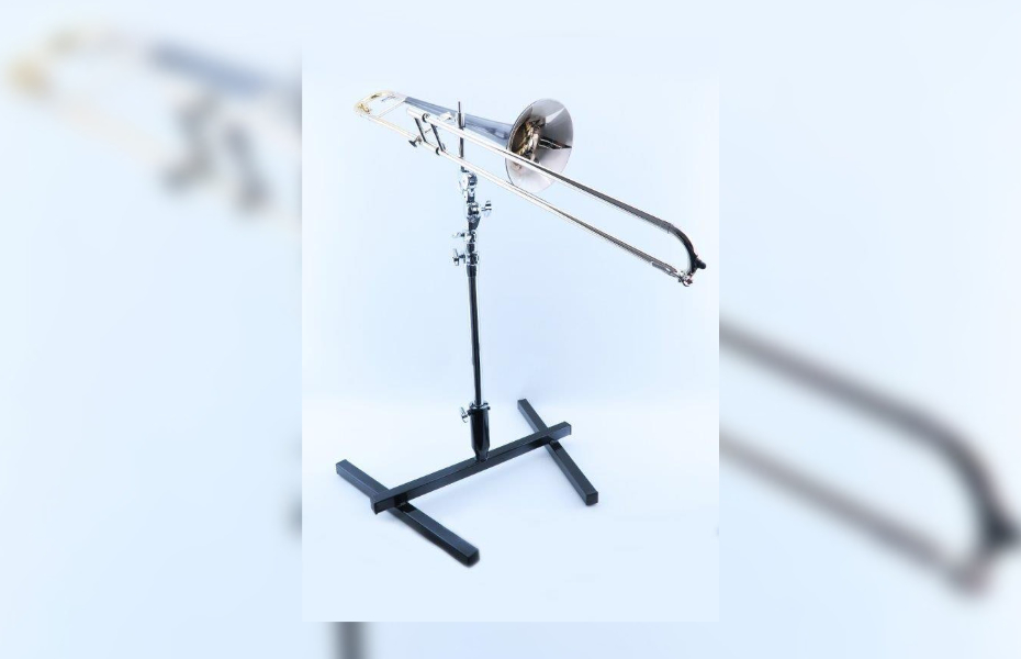 A silver trombone is fixed to a stand to enable the player to not have to hold it thus freeing up the hand to move the trombone.