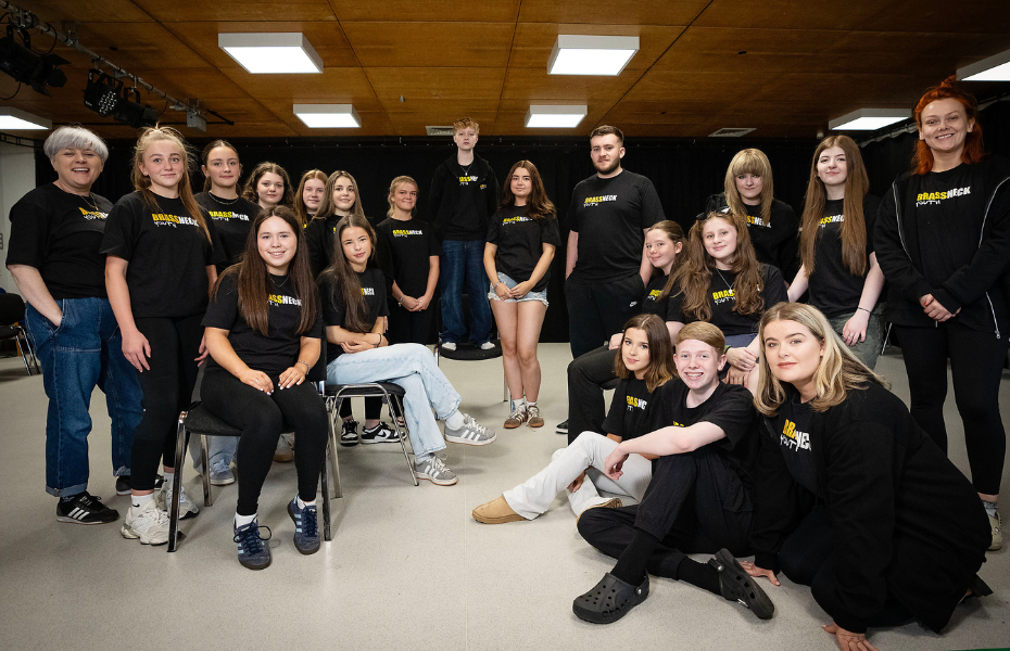 A group of young people in black t-shirts smiling at the camera.