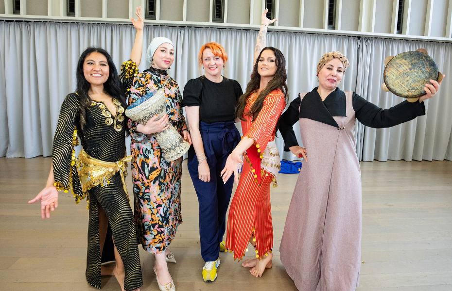 Five people standing in a dance pose smiling towards the camera.