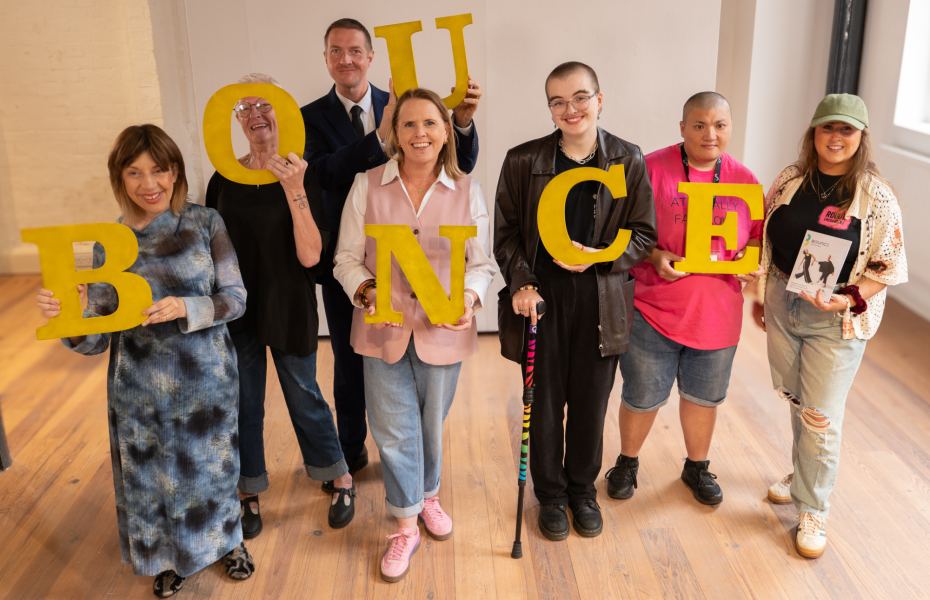 A group of people with disabilities holding individual yellow letters to spell out the word BOUNCE.