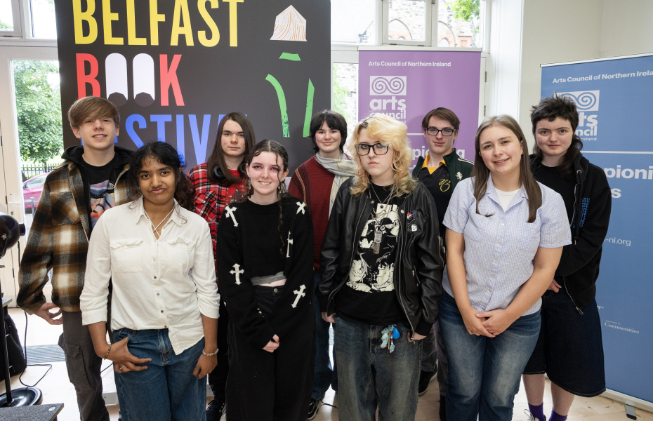 Young people standing together indoors smiling towards to the camera.