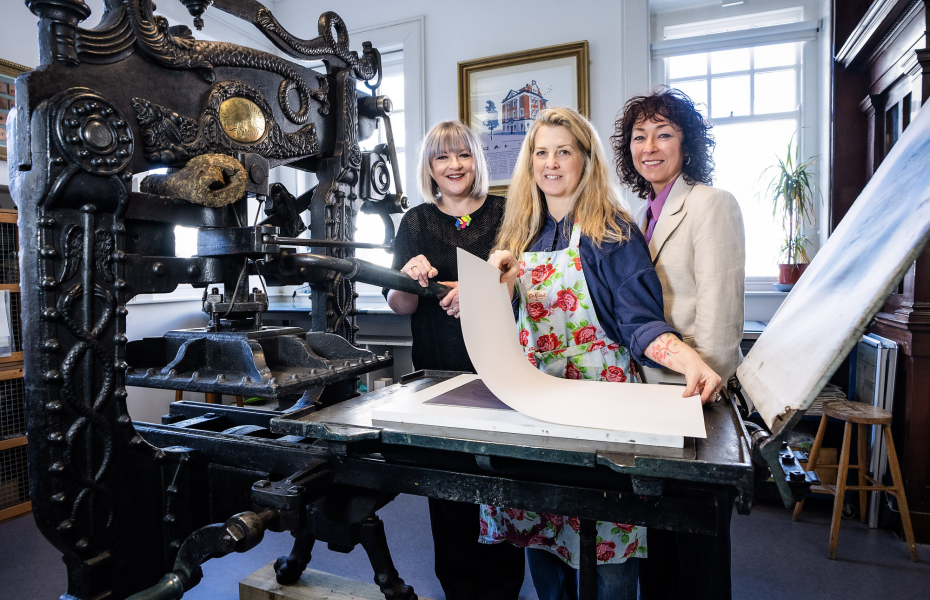 Image of three people in front of a large printing press