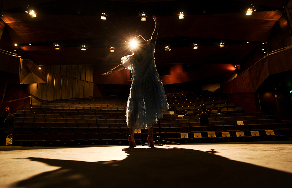 Dancer wearing blue dress performing on stage.