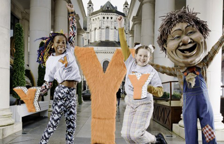 Two young girls jumping in St Anne’s Square Belfast wearing Young at Art branded t-shirts