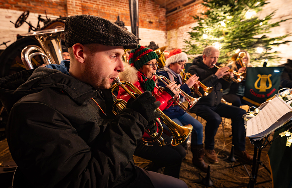 Brass band performing with Christmas tree in the background.