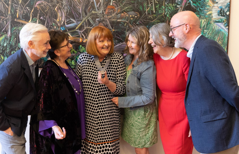 Five former Laureate na nÓg winners lean in to look at the new Laureate na nÓg who is holding her medal