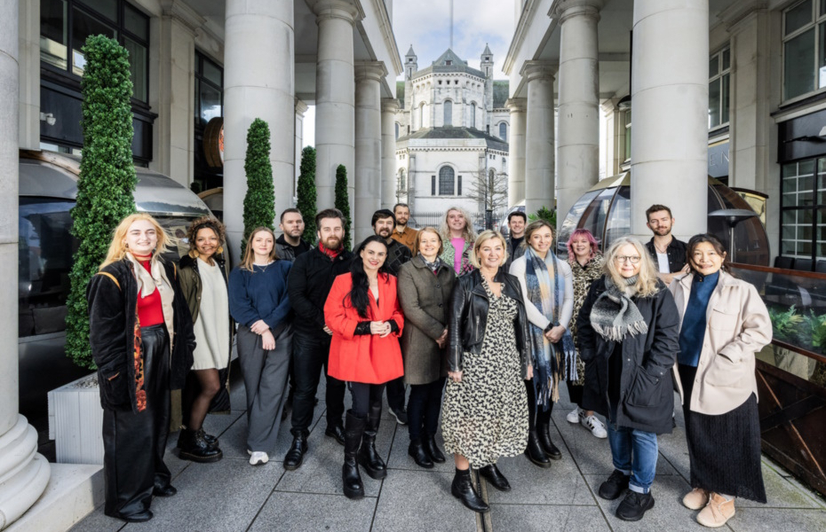 A group of artists standing outside in St Anne's Square in Belfast smiling towards the camera.